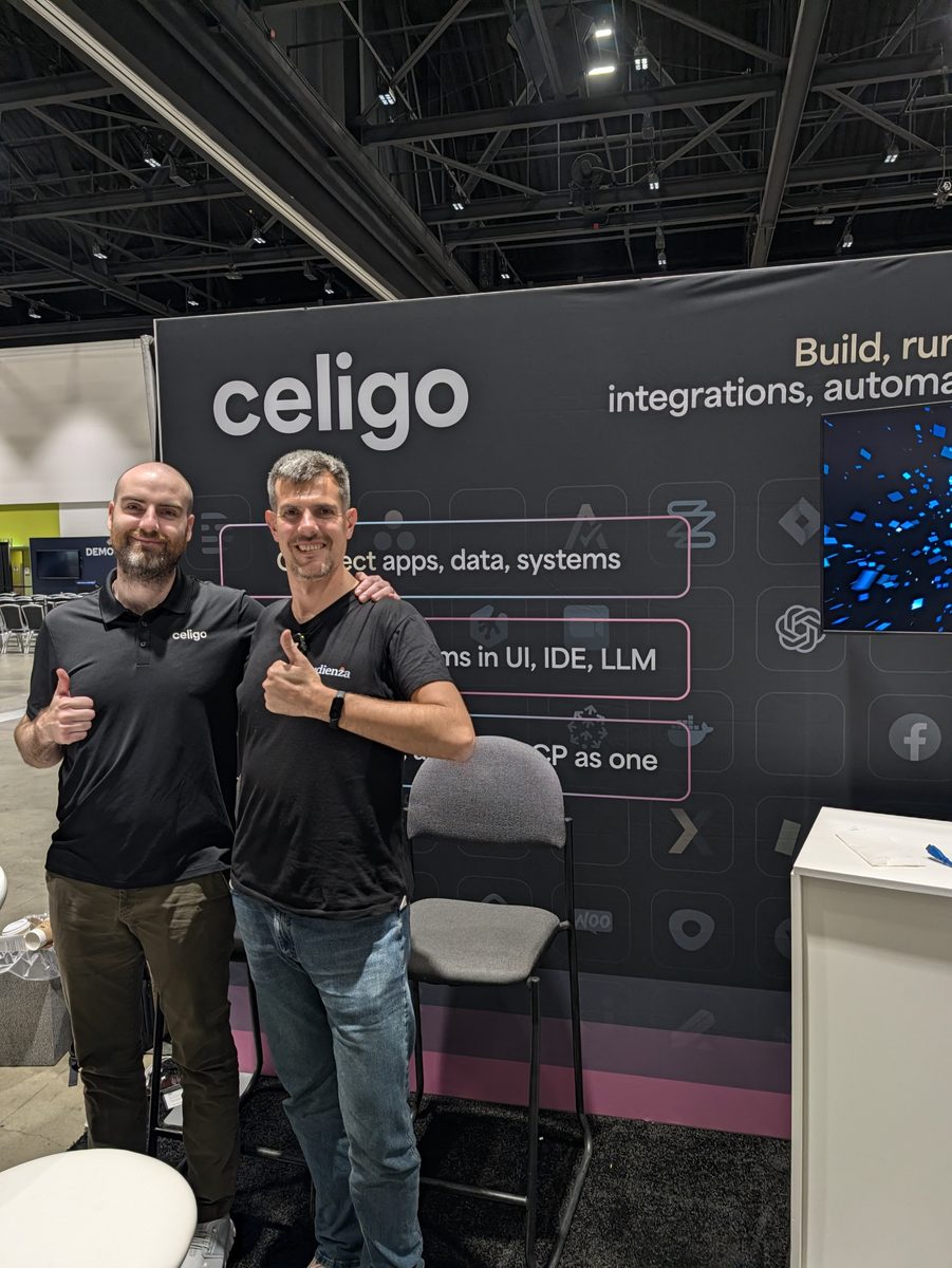 Luca Berton and Tyler Lamparter giving a thumbs-up in front of the Celigo booth wall: Build, run and govern integrations, automations