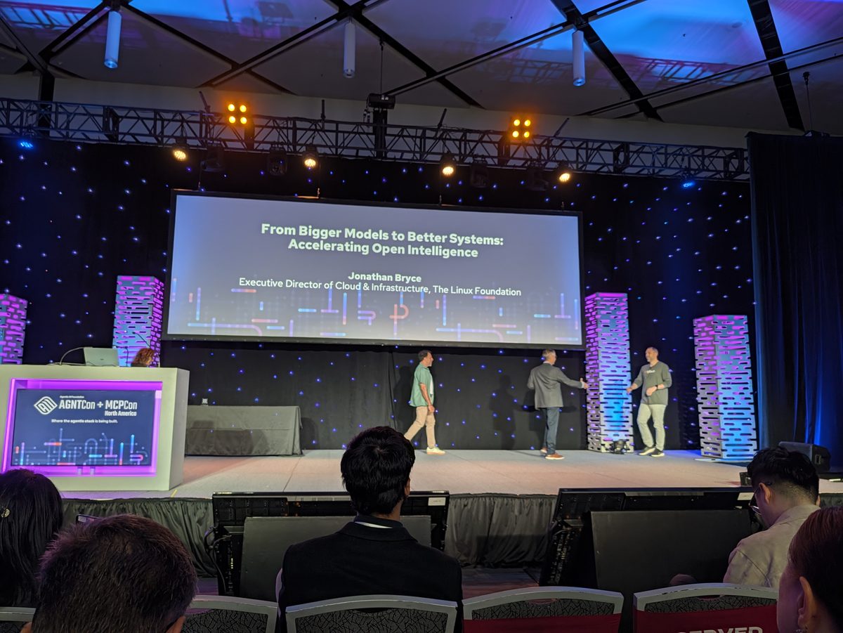 The keynote stage with the title slide From Bigger Models to Better Systems: Accelerating Open Intelligence, Jonathan Bryce, Executive Director of Cloud & Infrastructure, The Linux Foundation