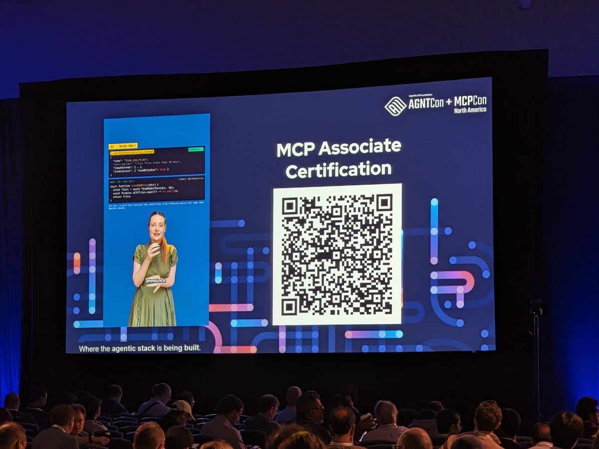 The keynote hall screen showing MCP Associate Certification with a QR code, above a seated audience