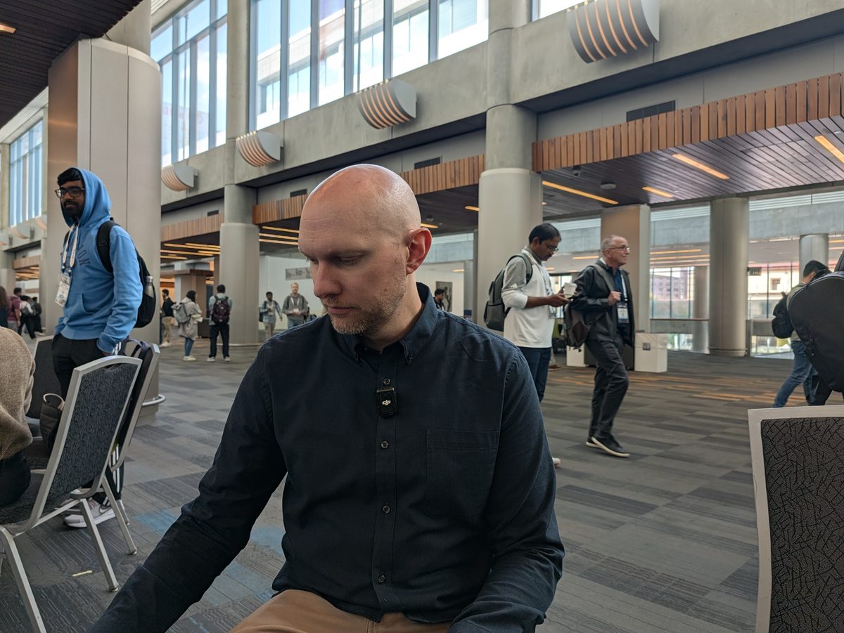 Matt Meeboer standing in a bright hall of the convention center, a lavalier microphone on his shirt