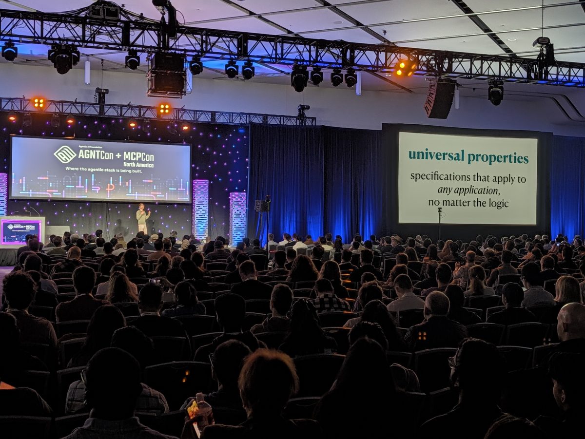 The keynote hall from the back, the side screen reading universal properties: specifications that apply to any application, no matter the logic