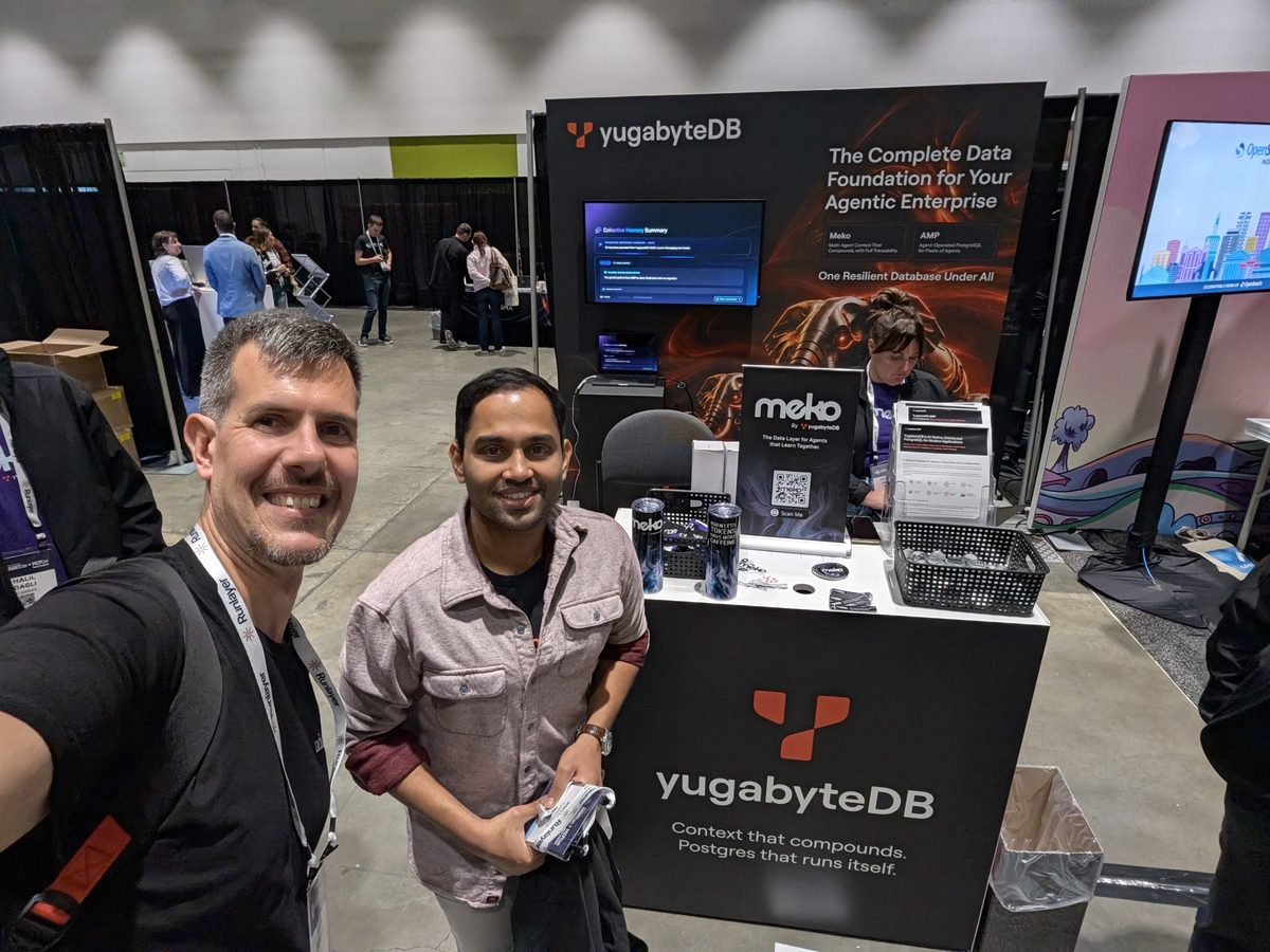 Luca Berton and Hari Krishna Sunder at the YugabyteDB booth, a Meko display on the counter behind them