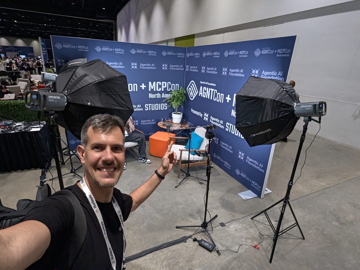 Luca Berton in front of the AGNTCon + MCPCon Studios backdrop in the Solutions Showcase, with softbox lights and a camera on a tripod