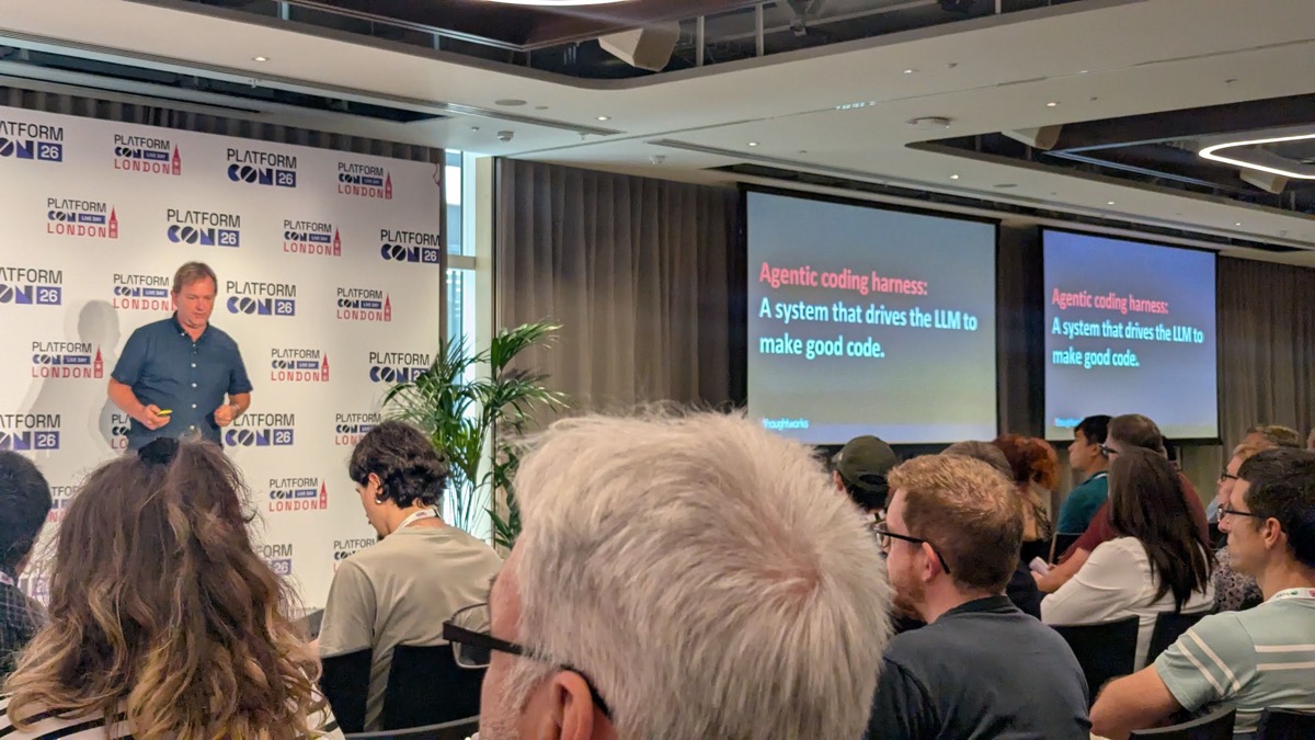 A speaker beside a slide reading: Agentic coding harness, a system that drives the LLM to make good code