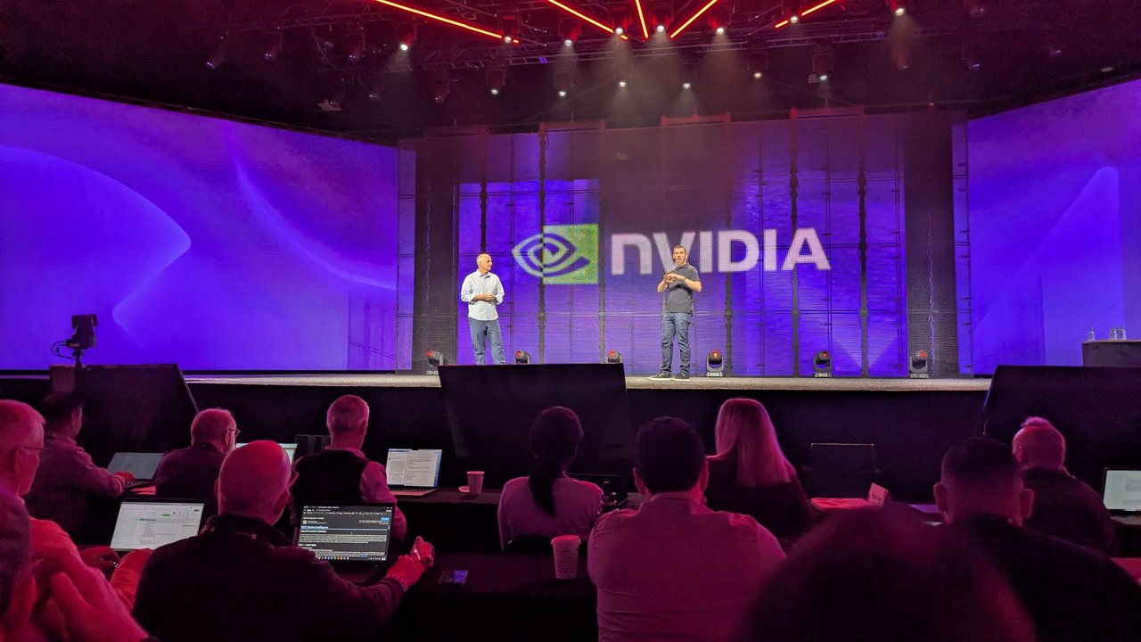 Two speakers on the Red Hat Summit keynote stage in front of a large NVIDIA logo, with the press rows in the foreground